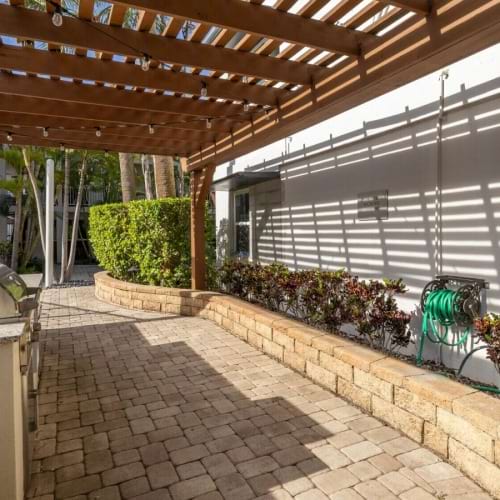 a patio with barbecue grills and plants and a wood roof